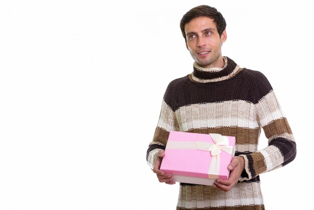 happy young handsome man smiling and thinking while holding gift box