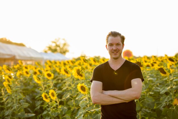 Happy young handsome man smiling with arms crossed in the field