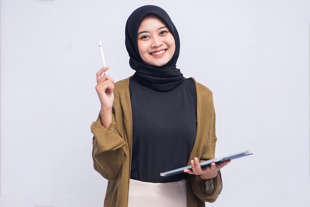 Счастливая молодая женщина в хиджабе, держащая ручку и буфер обмена в изоляции