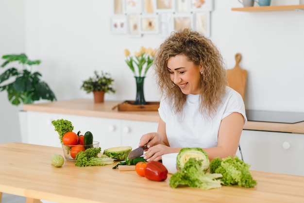 Счастливая молодая домохозяйка смешивает овощной салат
