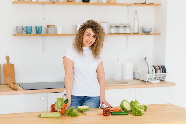 Happy young housewife mixing vegetable salad