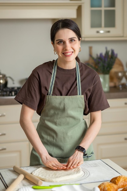 Happy young housewife preparing pastry in home kitchen