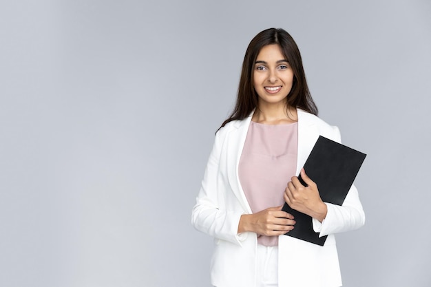 Happy young indian woman hold clipboard look at camera on grey studio background