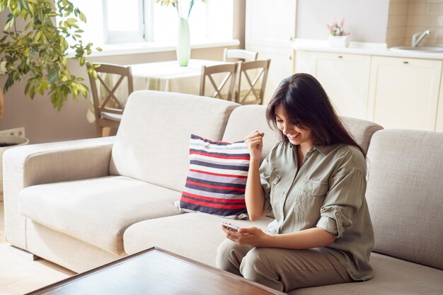 Photo happy young indian woman holding phone reading message celebrating success