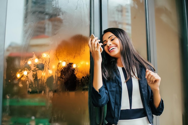 彼女の携帯電話を見て笑っている幸せな若いインドの女性