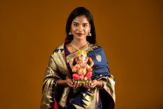 Happy young Indian woman posing with Ganesha statue on the occasion of Ganesh Festival