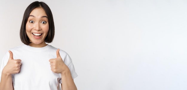 親指を立てて笑っている幸せな若い韓国人女性は、smthstanを推奨する正のフィードバックを与えます...