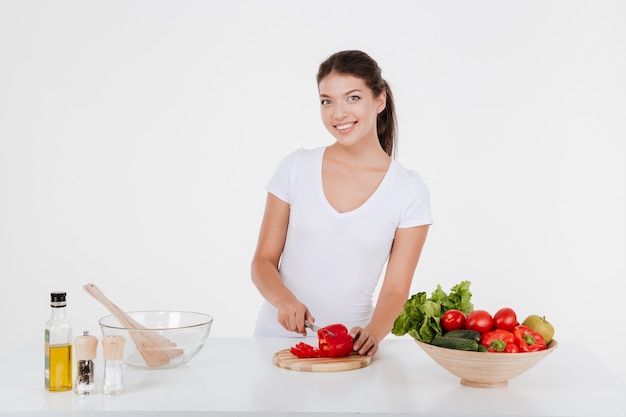 Happy young lady cooking with vegetables