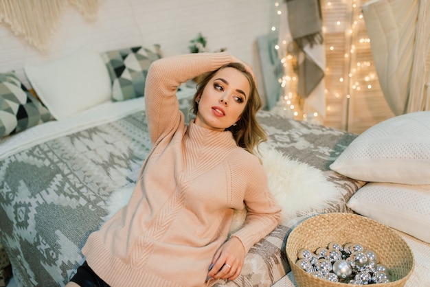 Happy young lady with long hair near the fireplace and the Christmas tree