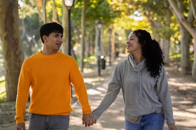 Happy young latin couple holding hands at park and looking at each other