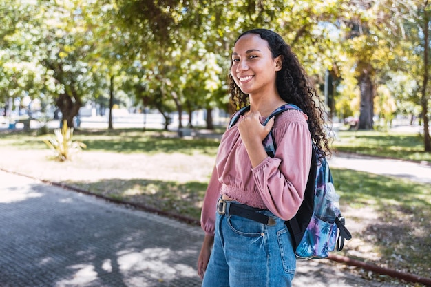 Happy young latin student woman standing in the park. Determination. Centennial generation