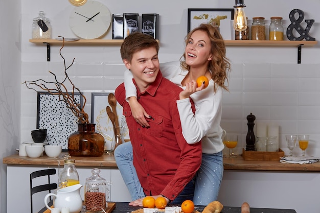 Photo happy young lovely couple on kitchen hugging each other. they enjoy spending time togehter. the man holding his girlfriend