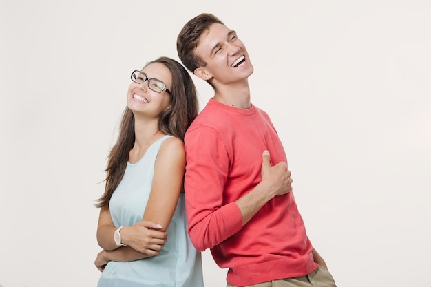 Happy young lovely couple standing back to back and laughing