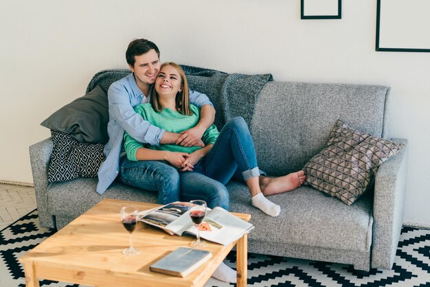 Happy young lovers hugging on cozy couch