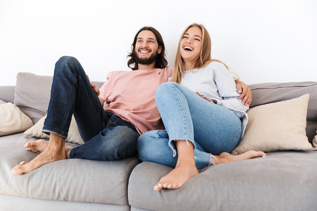 Photo a happy young loving couple on sofa watch tv film indoors at home.