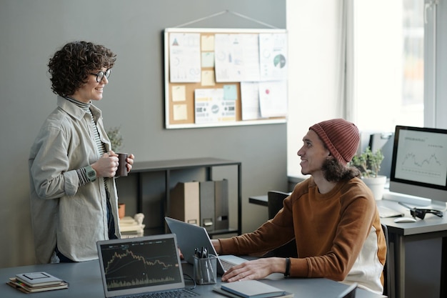 Happy young male analyst or broker looking at female colleague