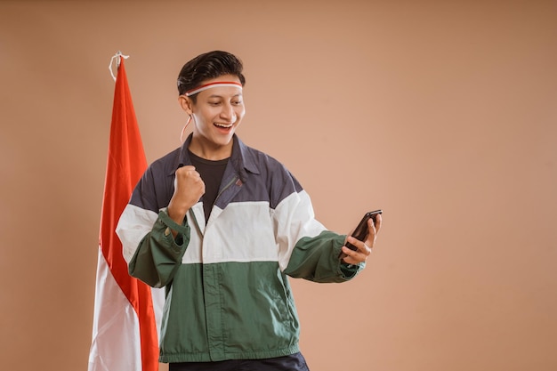 사진 고립된 배경에서 휴대폰을 사용하는 행복한 젊은 남성 운동선수