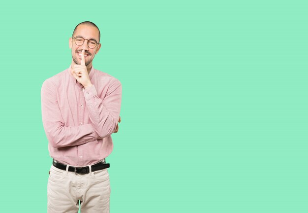 Happy young man asking for silence gesturing with his finger