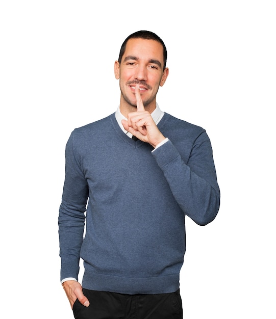 Happy young man asking for silence gesturing with his finger