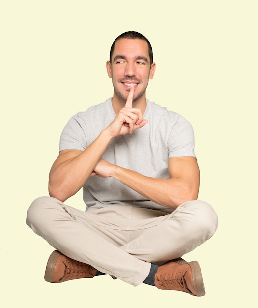 Happy young man asking for silence gesturing with his finger