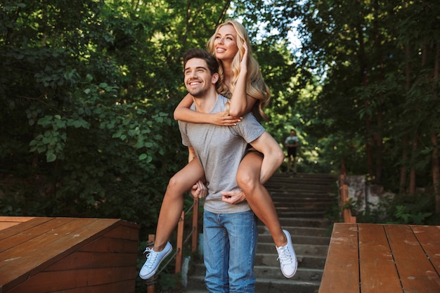 Happy young man carrying his pretty girlfriend