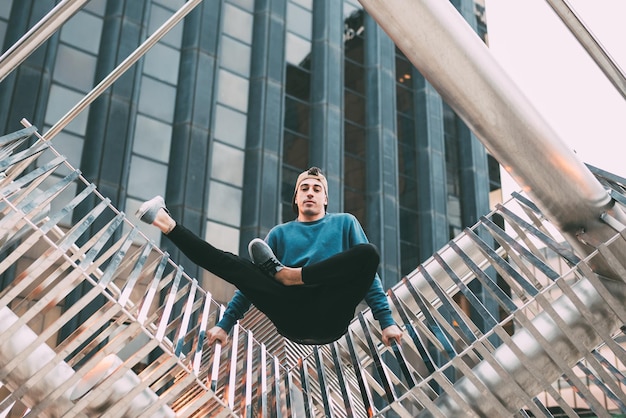 Happy young man doing acrobatic poses in a metal sculpture xA