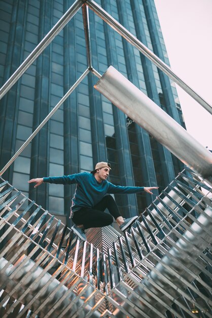 Happy young man doing acrobatic poses in a metal sculpture xA