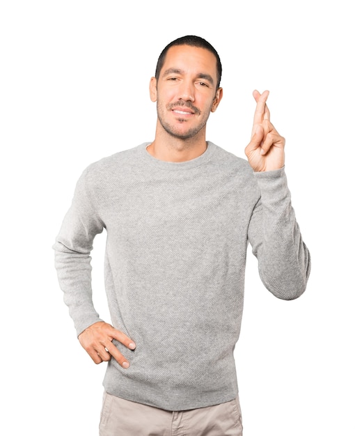 Happy young man doing a crossed fingers gesture