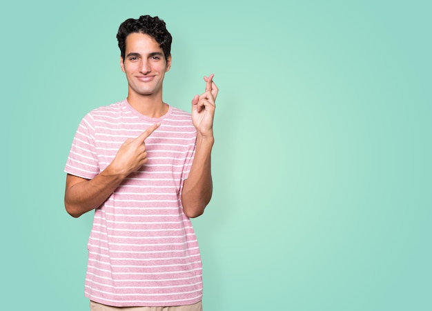 Happy young man doing a crossed fingers gesture