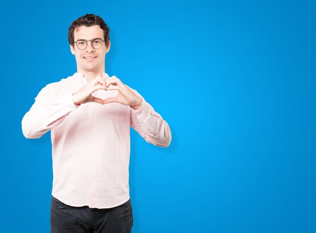 Happy young man doing a gesture of love with his hands