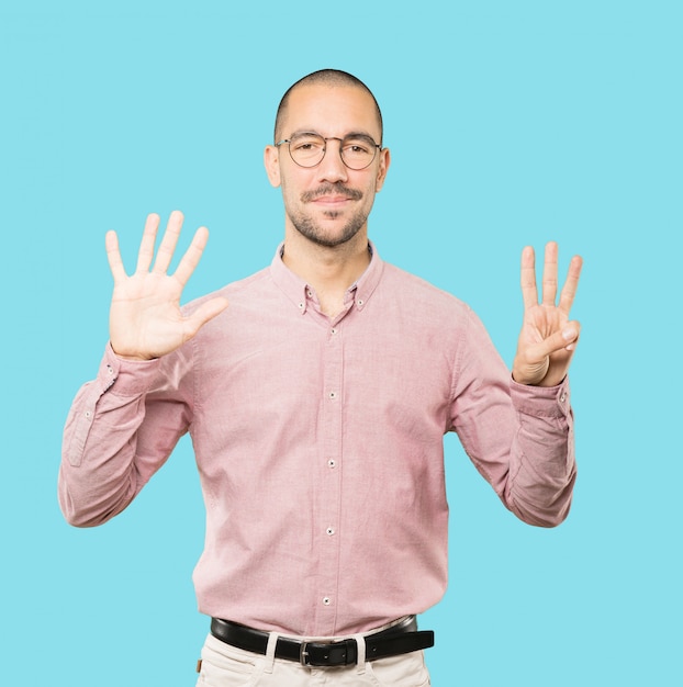 Счастливый молодой человек делает жест номер восемь своими руками