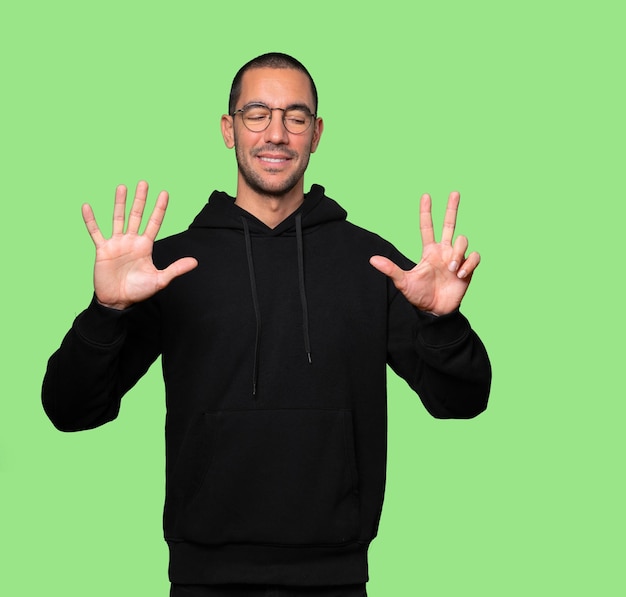 Happy young man doing a number eight gesture with his hands