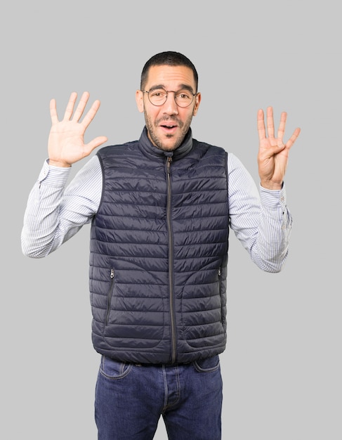 Happy young man doing a number nine gesture with his hands