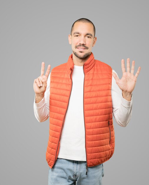 Happy young man doing a number seven gesture with his hands