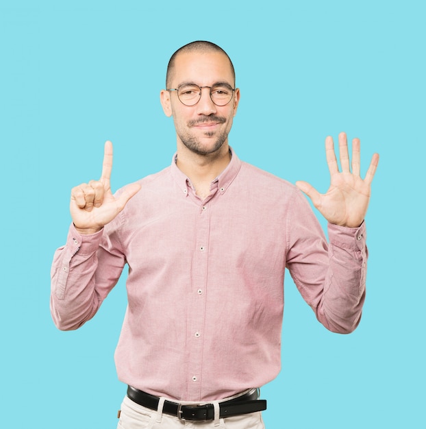 Photo happy young man doing a number seven gesture with his hands