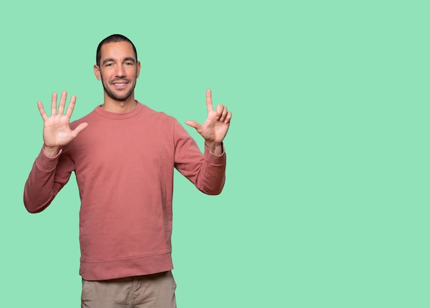 Happy young man doing a number seven gesture with his hands