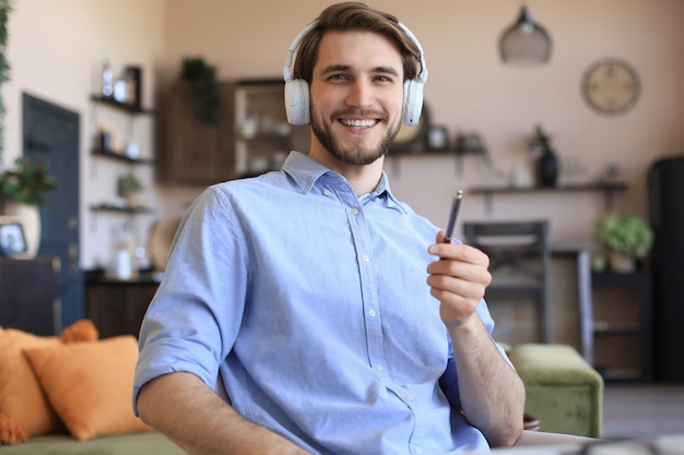 Happy young man in earphones working from home during self isolation.