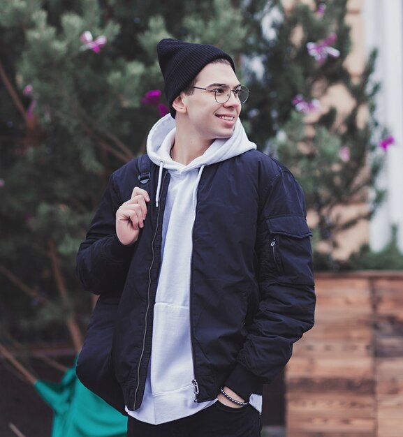 Happy young man in glasses holding his backpack