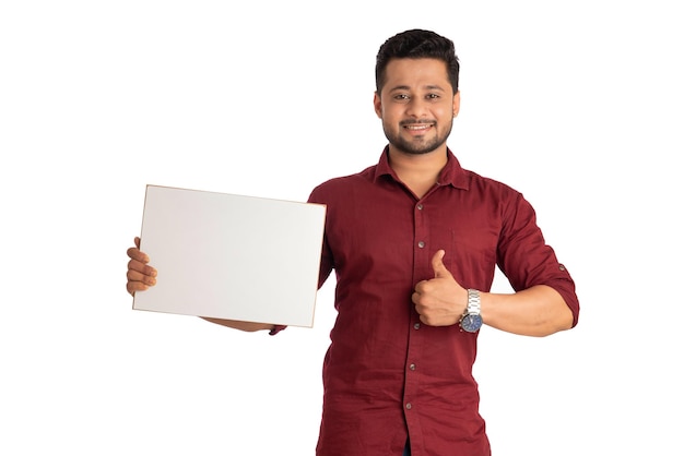 A happy young man holding and displaying a signboard or placard in his hands on a white background