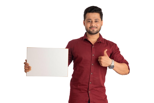 A happy young man holding and displaying a signboard or placard in his hands on a white background