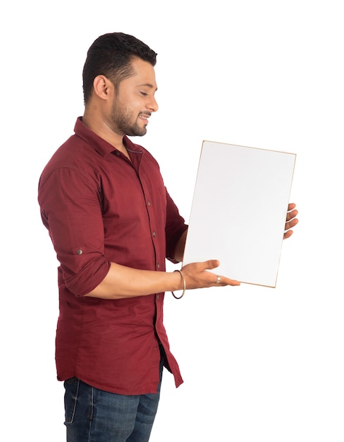 A happy young man holding and displaying a signboard or placard in his hands on a white background