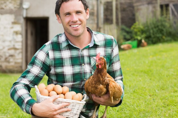 彼の鶏と卵のバスケットを保持している幸せな若い男