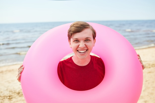 Photo happy young man holding swim tube at beach