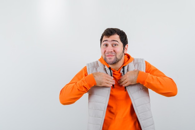 The happy young man is showing himself by clasping hands on chest on white background