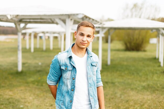 Happy young man in jeans and a white T-shirt near white canopies in the nature