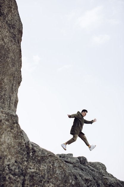 Happy young man jumping out of rock. The concept of success