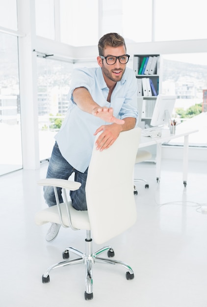 Happy young man kneeling on chair in office