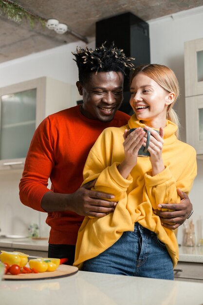 happy young man laughing and hugging his beloved girlfriend while standing in the kitchen with her