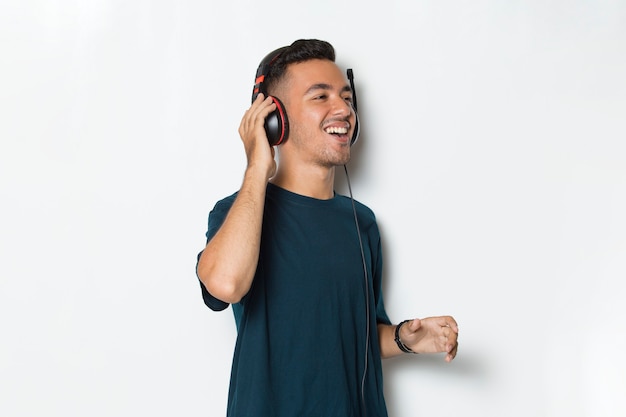 Happy young man listening music dancing and having fun on white background