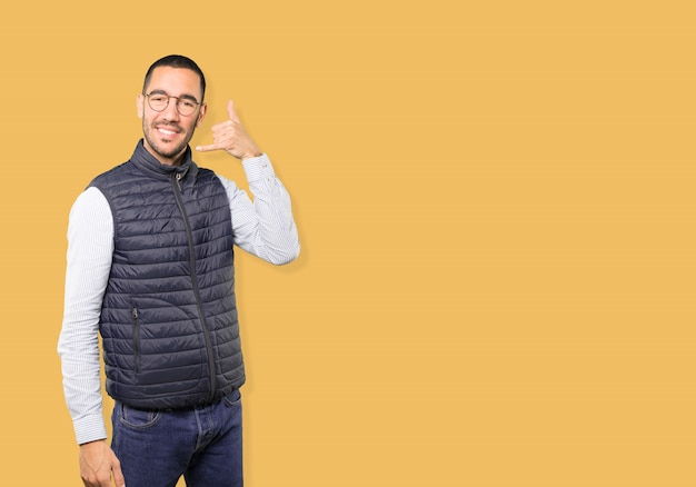 Happy young man making a gesture of calling with the hand